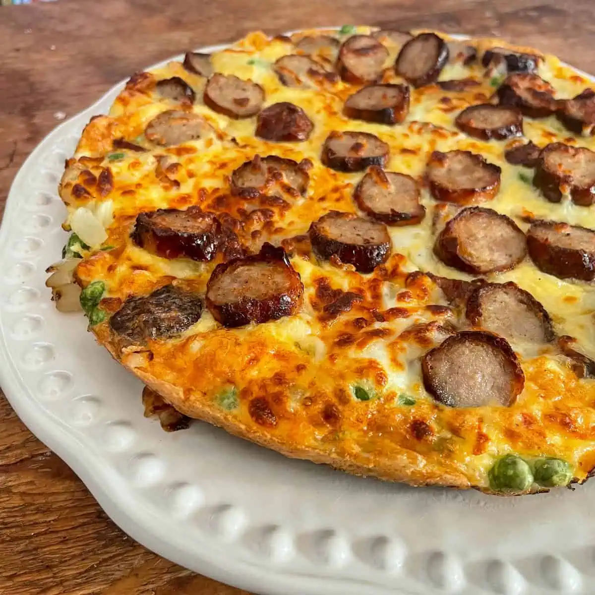 Cheesy sausage frittata with peas on a white plate