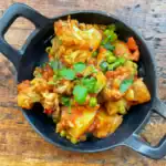 aloo gobi overhead view in a cast iron pan on a wooden table