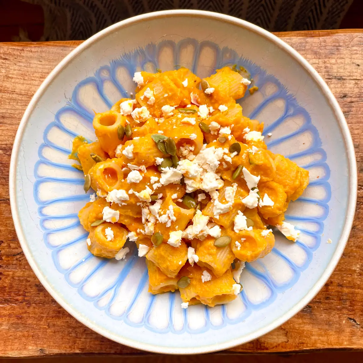 butternut squash pasta topped with feta in a blue bowl