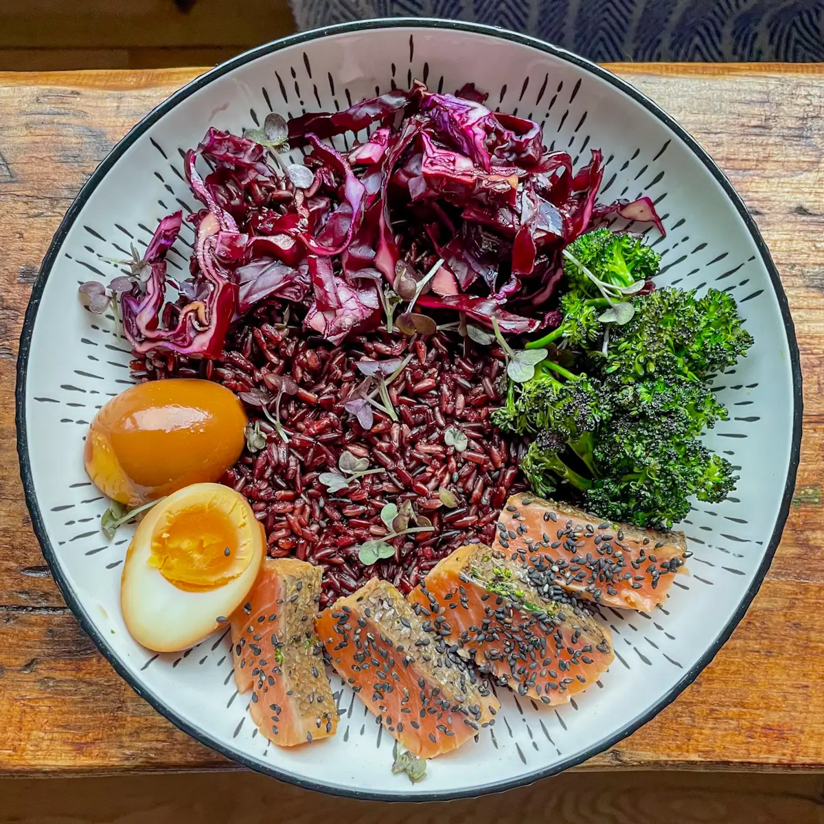 Salmon rice bowl topped with eggs, broccoli and cabbage