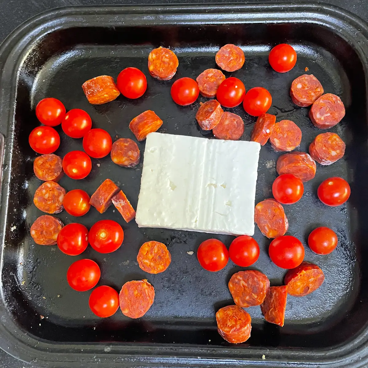 feta, chorizo and tomatoes in a pan ready to go in the oven