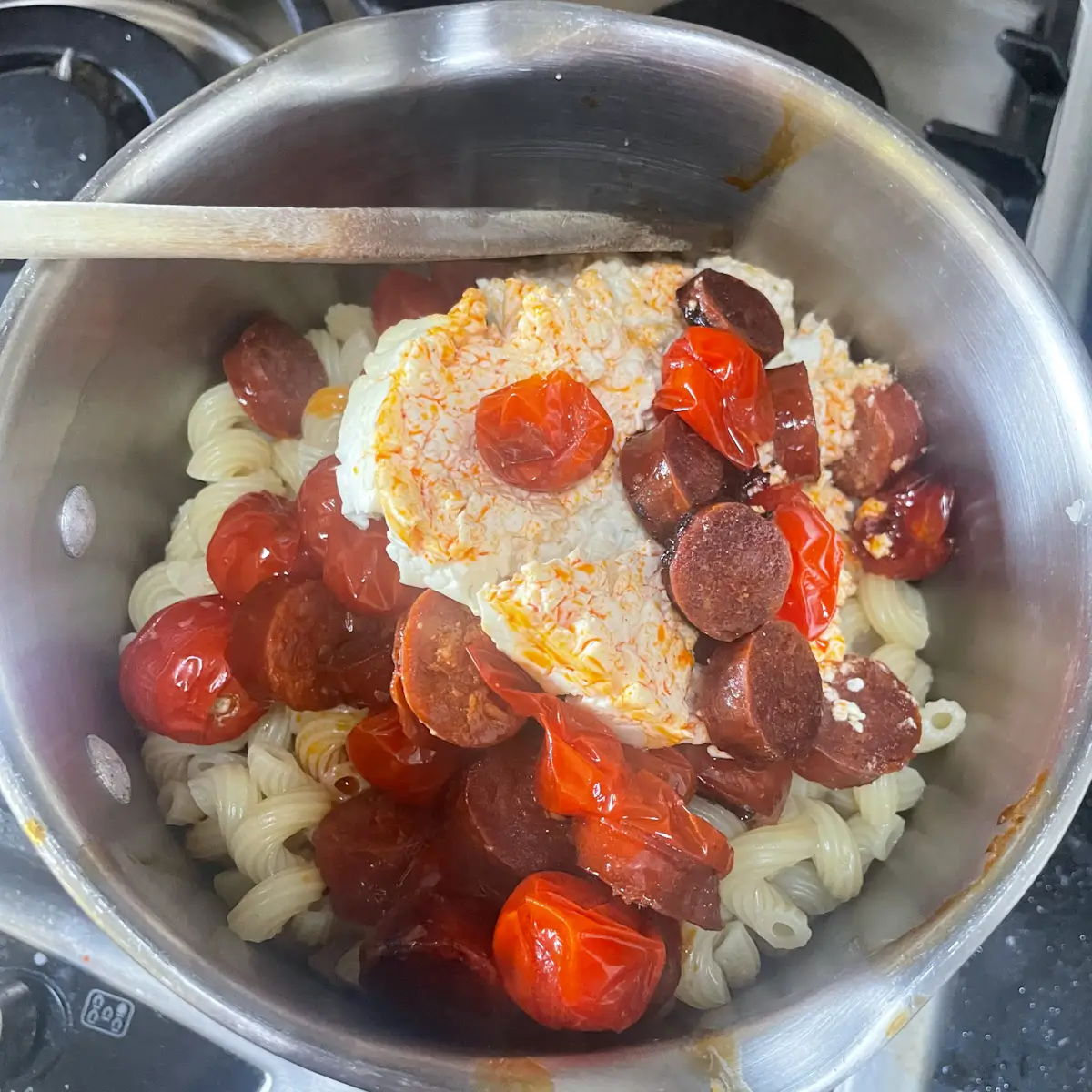 pasta, feta, chorizo and tomatoes in a pan ready to stir