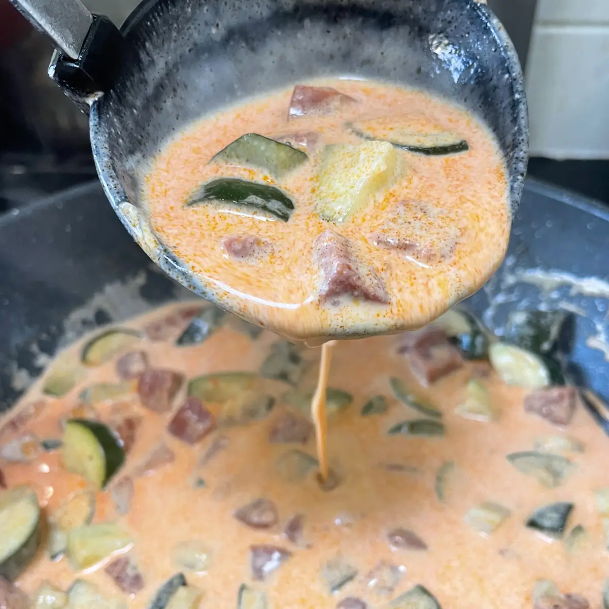 creamy chorizo sauce for pasta pouring from a ladle