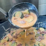 creamy chorizo and courgette sauce in a pan with a ladle