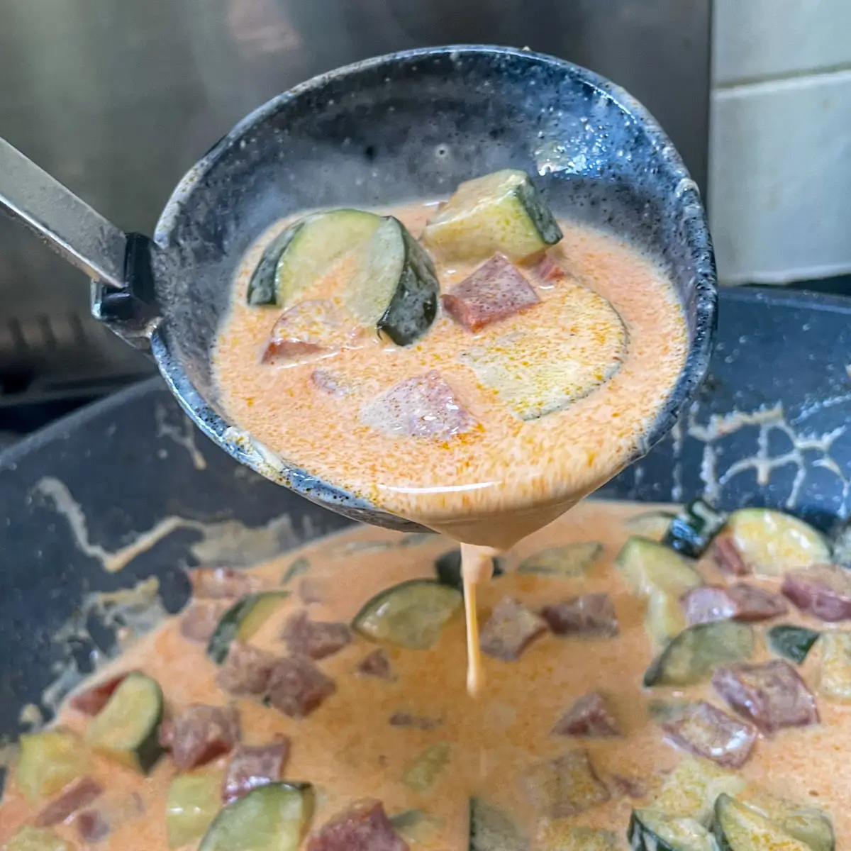 creamy chorizo and courgette sauce in a pan with a ladle