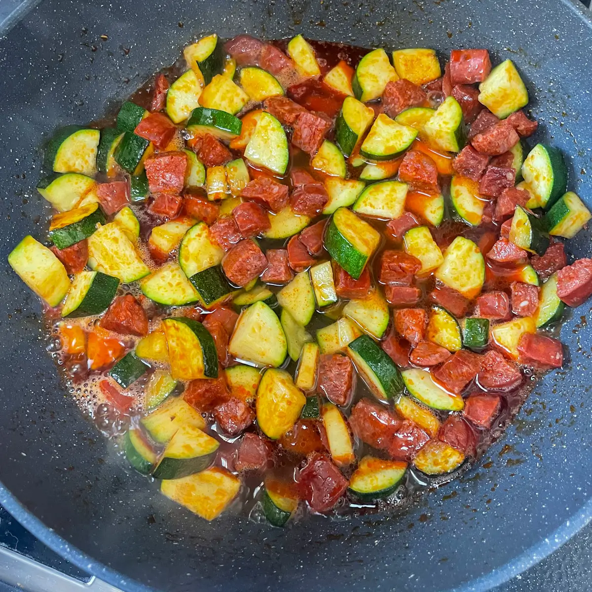 white wine reducing in a pan with chorizo and courgette
