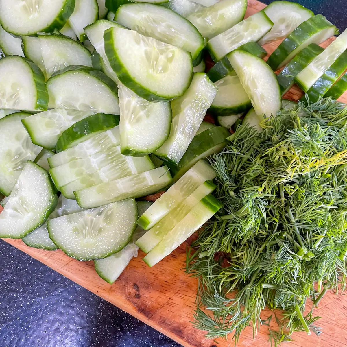 sliced cucumber and chopped dill on a chopping board