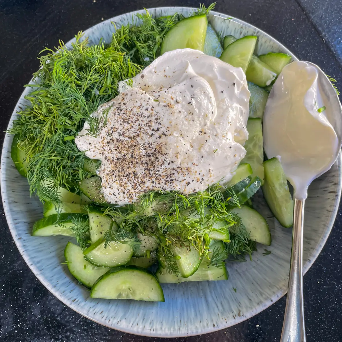 adding all ingredients for cucumber salad to a bowl