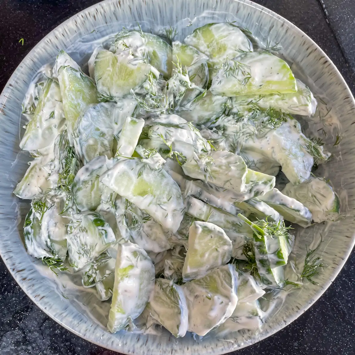 sliced cucumbers mixed with dill and soured cream