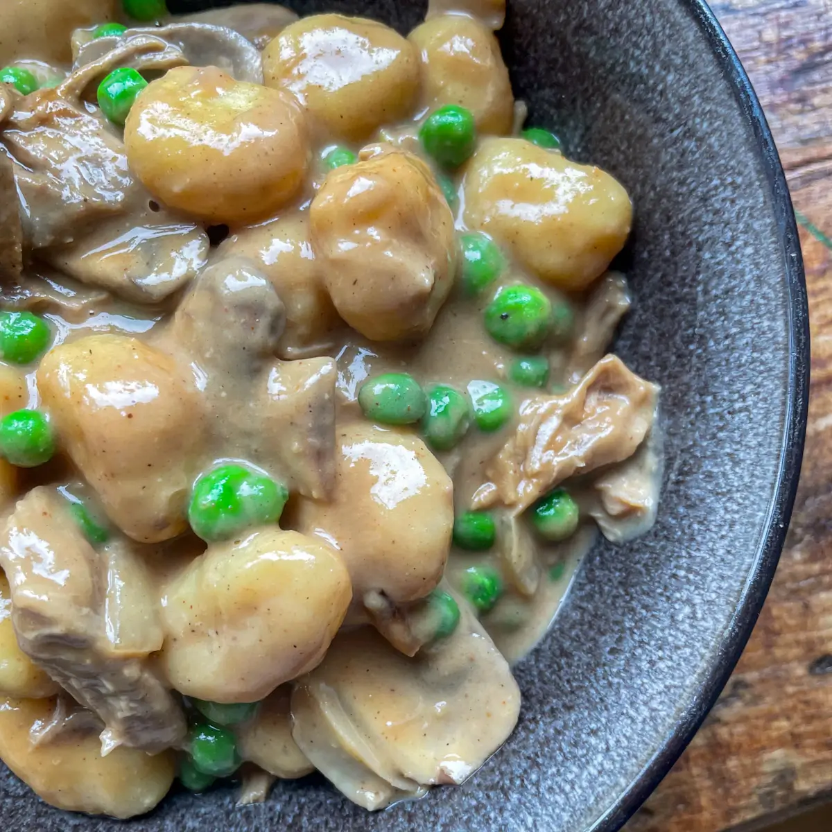 close up of golden gnocchi with duck, mushrooms and peas