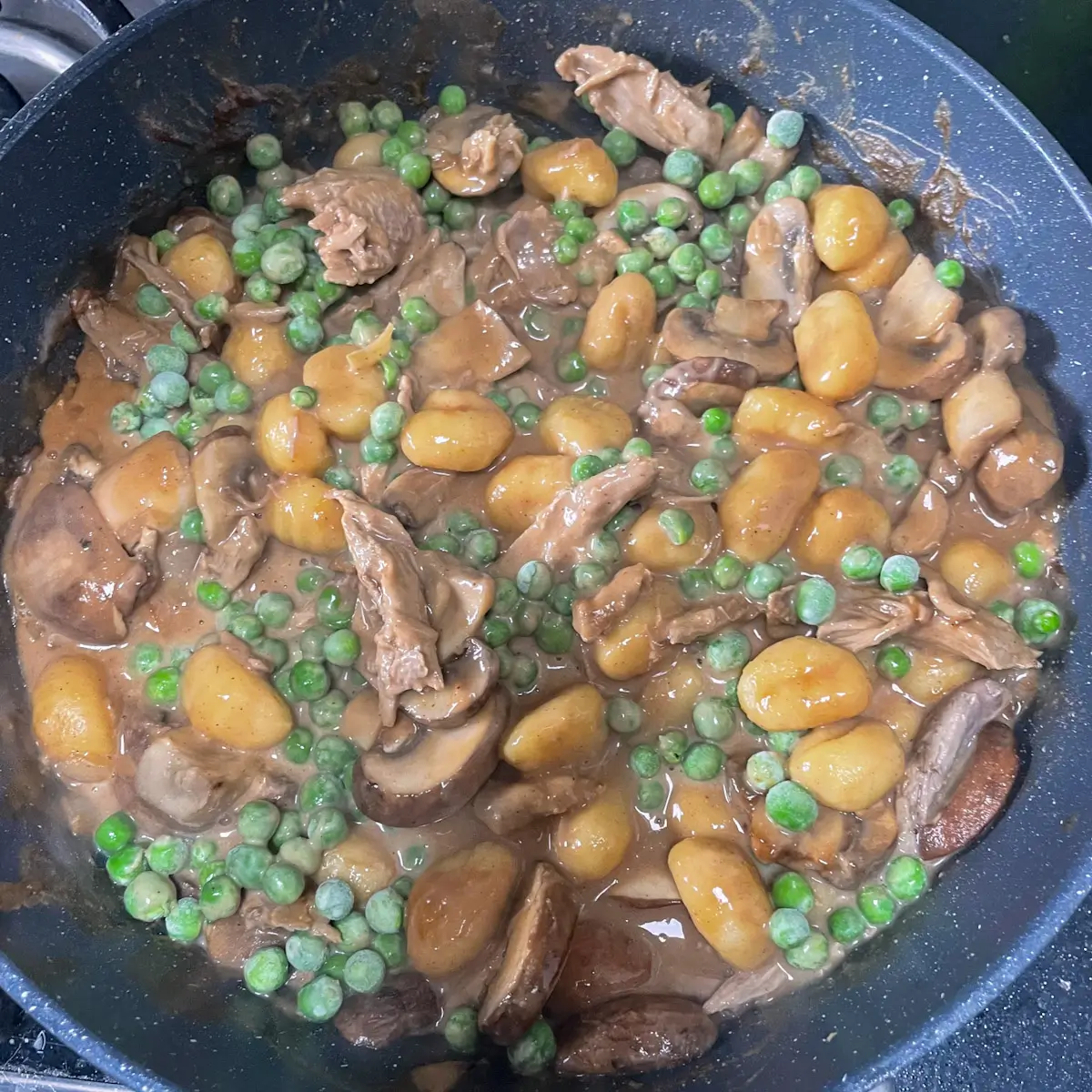adding peas to the saucy duck gnocchi