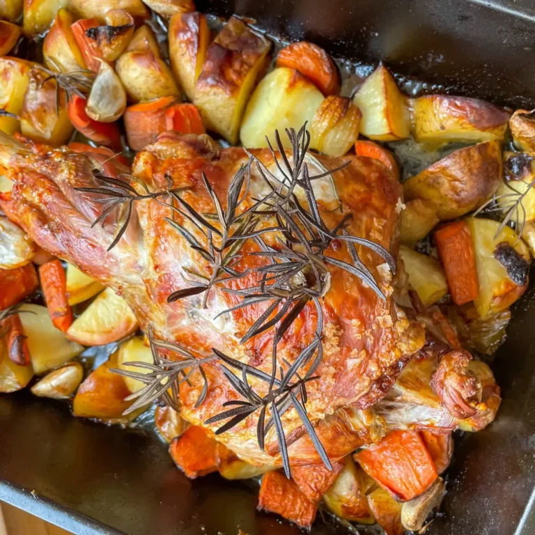 golden skinned roast lamb on top of roasted vegetables