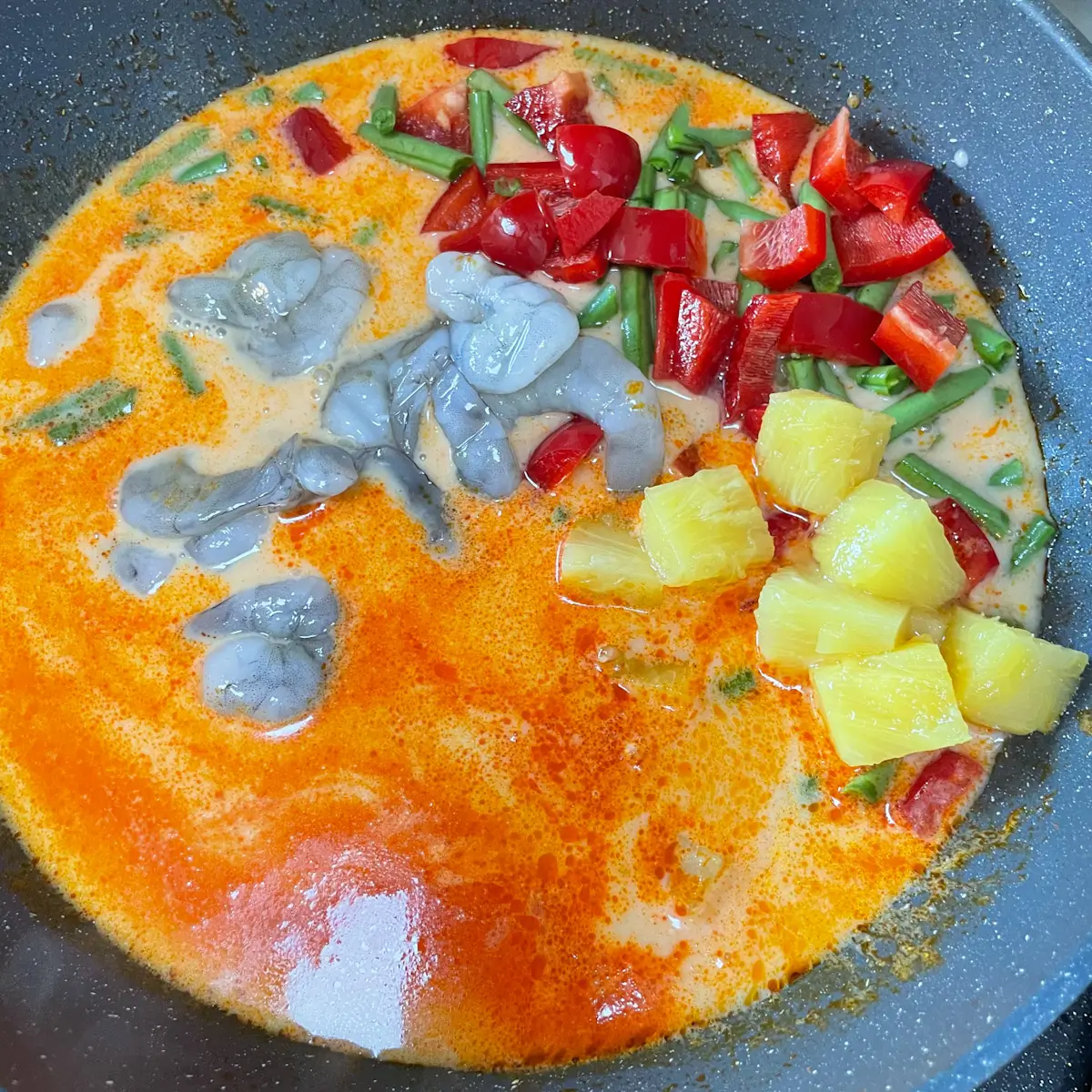 adding the prawns, pineapple, green beans and red pepper