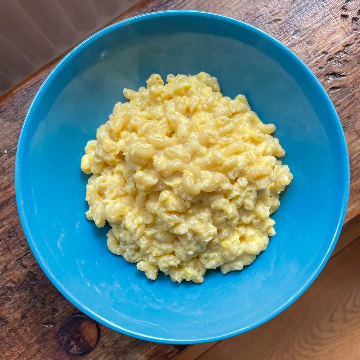 overhead image of hidden veg pasta with sweetcorn in a blue bowl