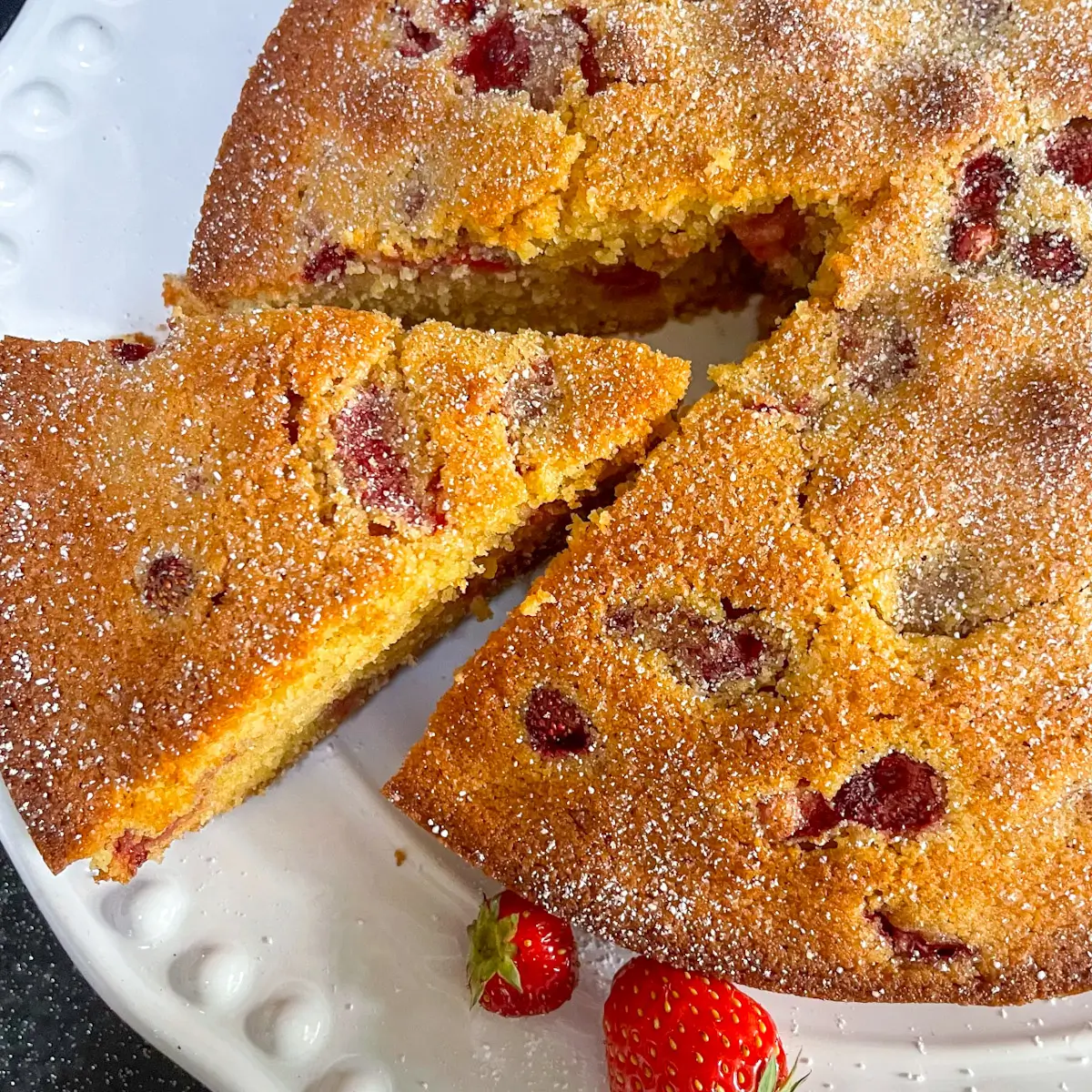 wild strawberry cake with a slice cut out of it on a white plate
