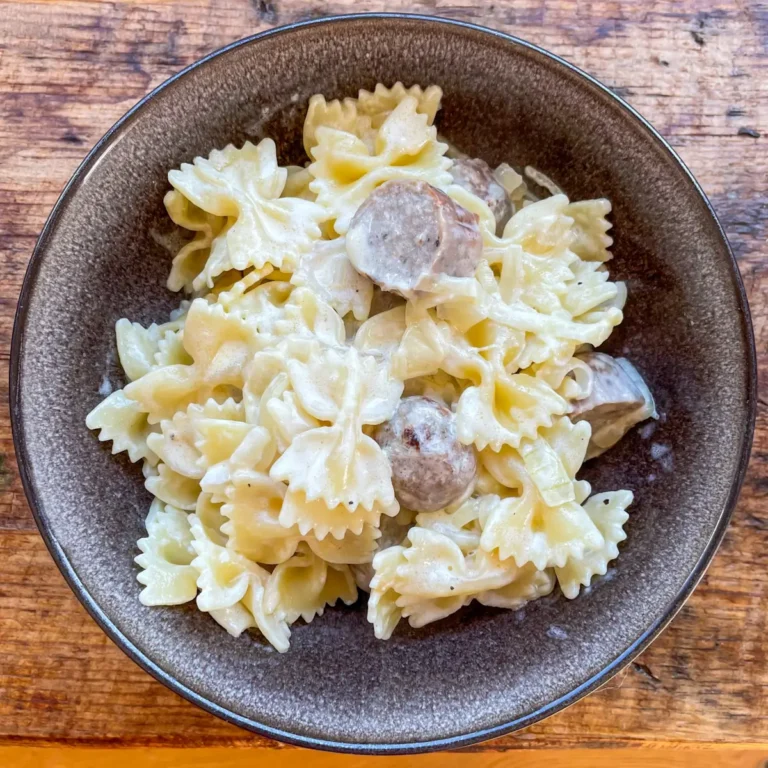 caramelised onion and sausage pasta in a black bowl
