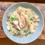 chicken caesar pasta topped with crunchy breadcrumbs in a blue bowl