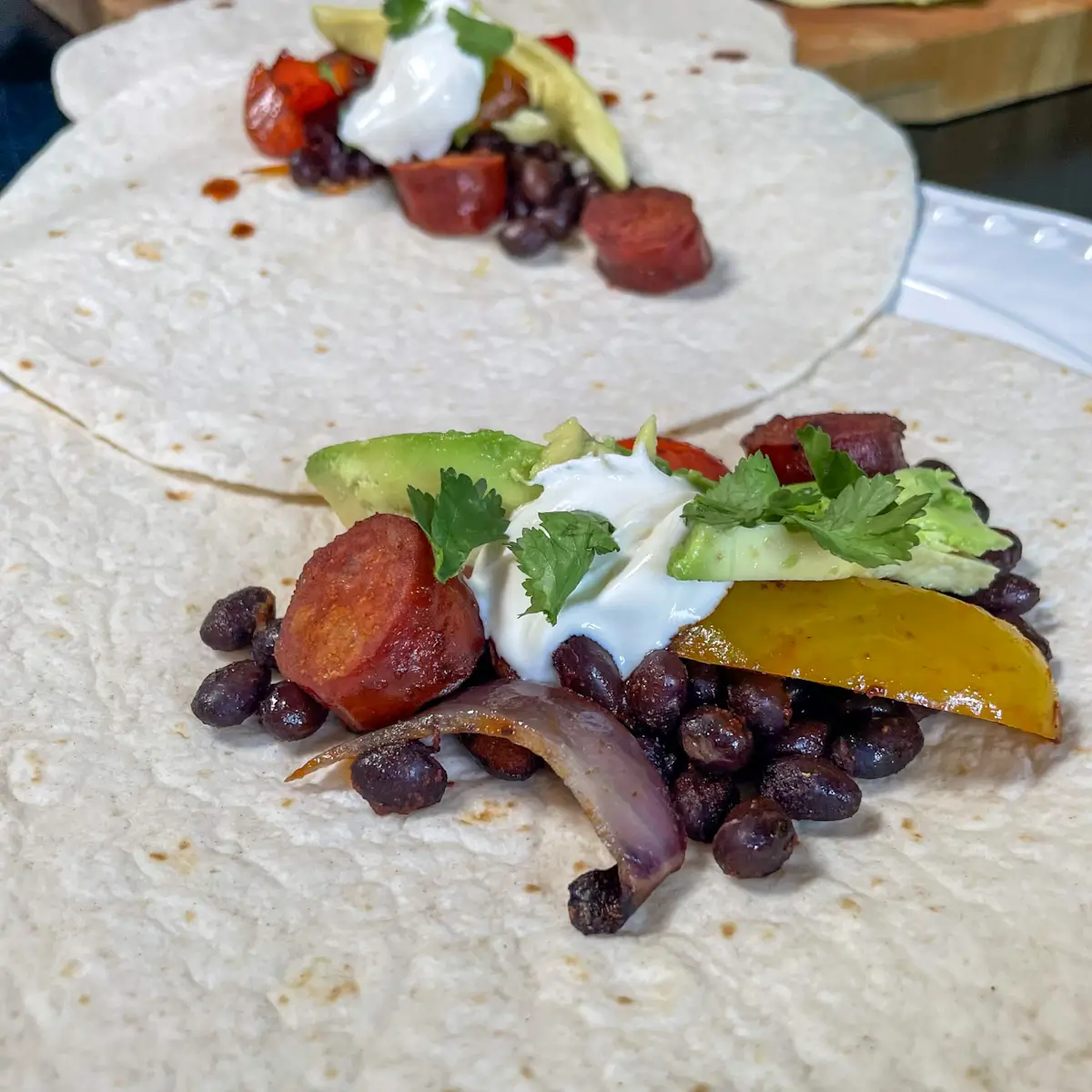 chorizo and black bean fajita mix on wraps with soured cream and avocado