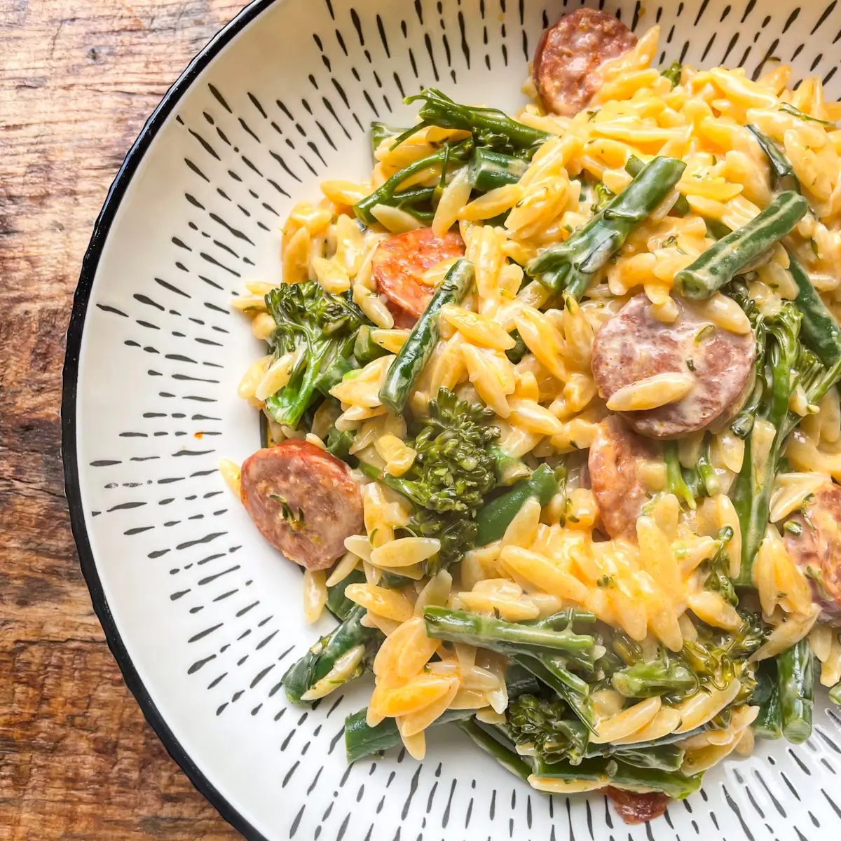 close up of a creamy chorizo orzo dish in a white bowl