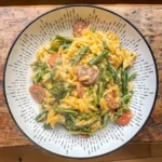 one pot chorizo orzo with green beans and broccoli in a white bowl