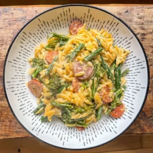 one pot chorizo orzo with green beans and broccoli in a white bowl