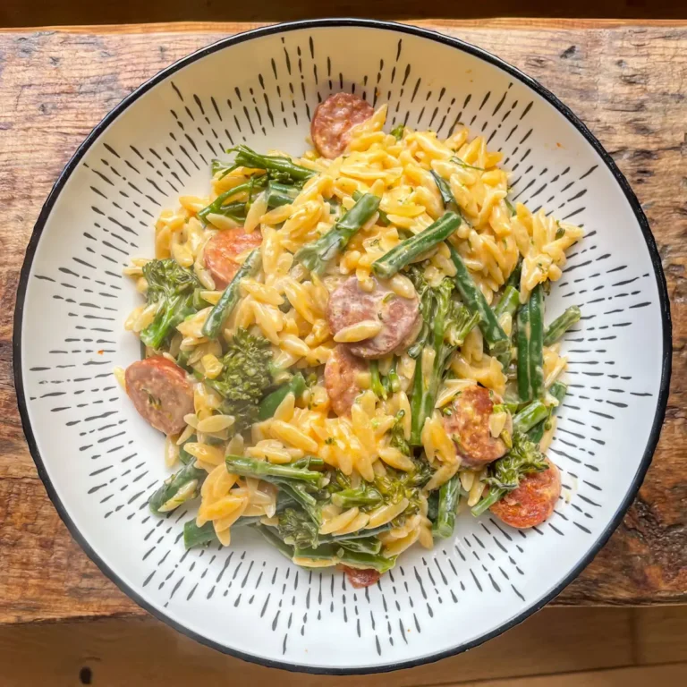 one pot chorizo orzo with green beans and broccoli in a white bowl