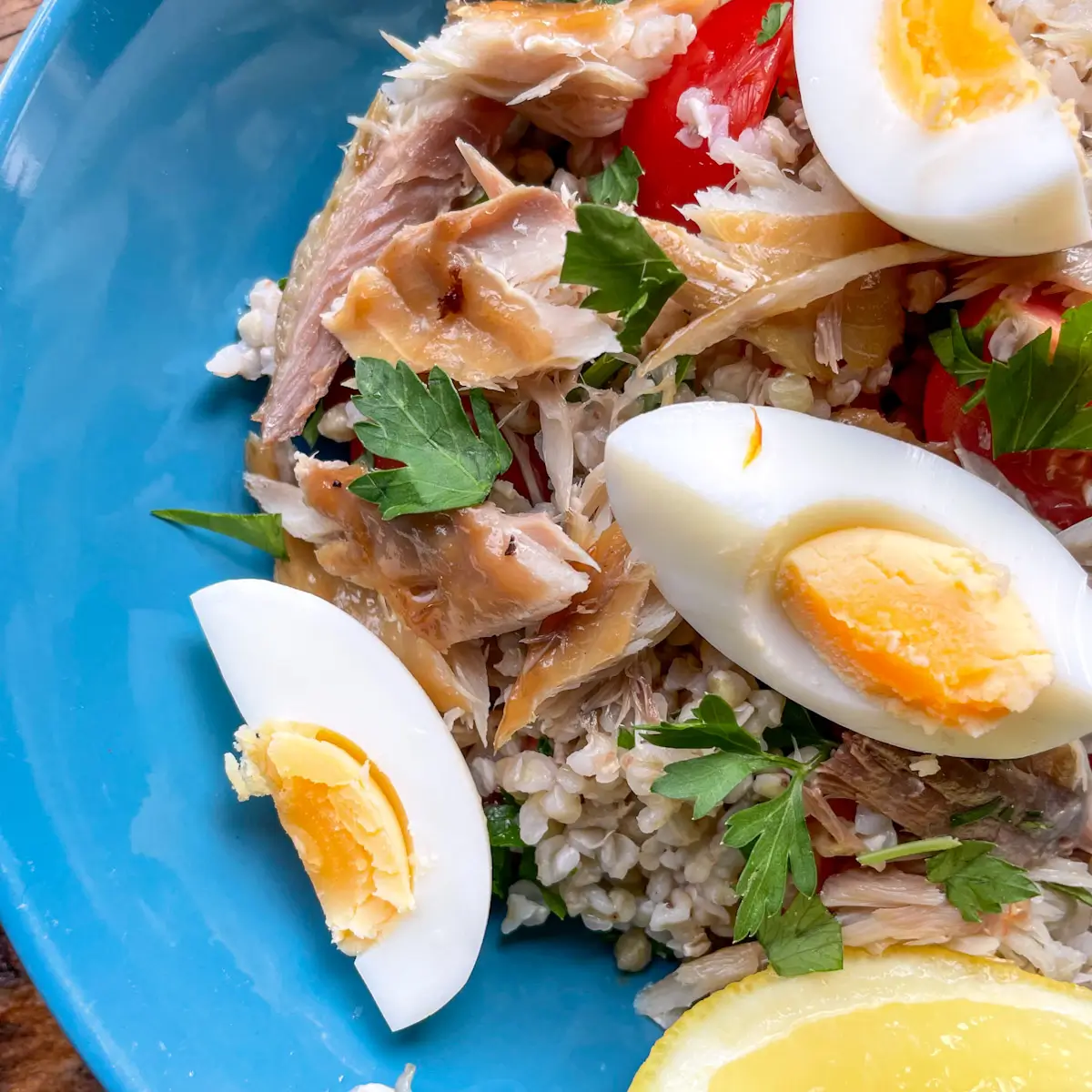 Mackerel and buckwheat salad in a blue bowl topped with boiled egg