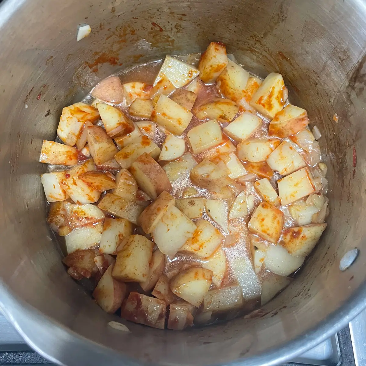 Potatoes for saag aloo simmering with curry powder and water