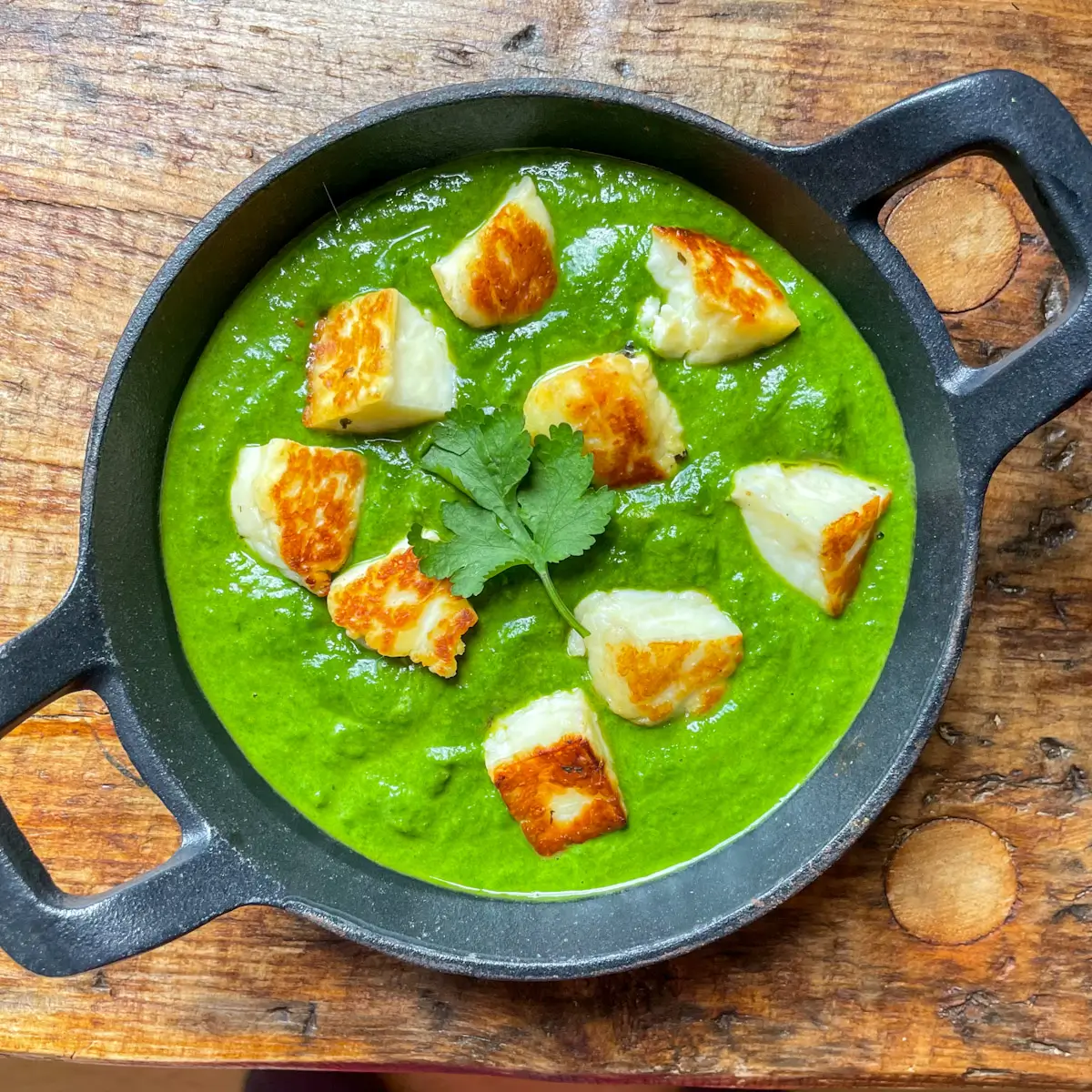 Creamy spinach curry topped with golden halloumi in a cast iron dish
