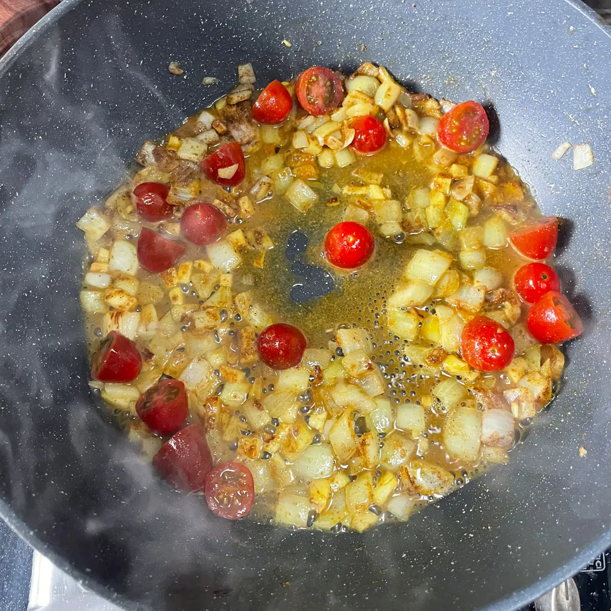 Cooking onions, ginger, garlic, tomatoes and spices in a pan