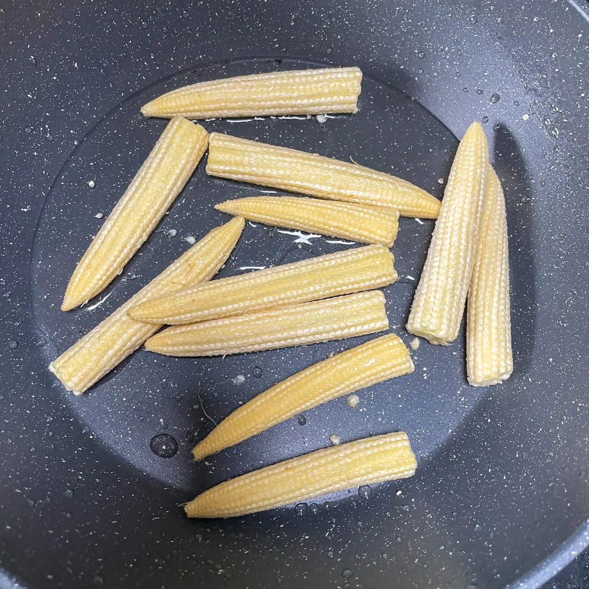 cooking baby corn in a pan